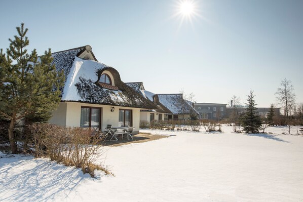 A snow-covered building with a patio area and a clear sky.