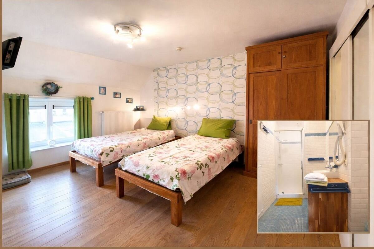 A bedroom with two wooden beds, a window with curtains, a radiator, and a wall with circular patterns.