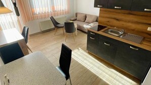A modern kitchen with a wooden countertop, black cabinets, and a dining area with a table and chairs. - Apartment Beulig-Tietz 2 - Apartment Beulig-Tietz GM 69105 (Graal-Müritz)