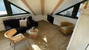 A room with a black sofa, wicker chairs, a small table, and a TV. - Apartment Beulig-Tietz 2 - Apartment Beulig-Tietz GM 69105 (Graal-Müritz)