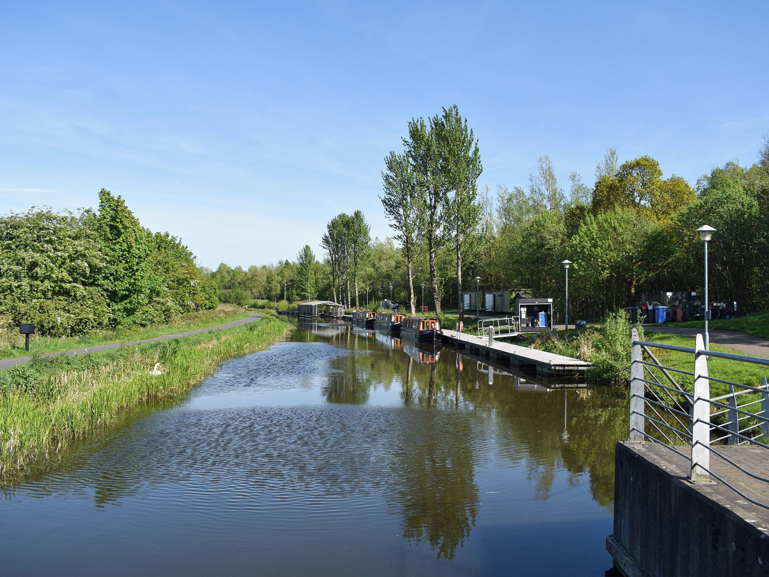 Un canal avec des bateaux, un quai en bois et un petit bâtiment.