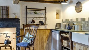 Una cocina rústica con muebles de madera, una tetera antigua y electrodomésticos modernos.