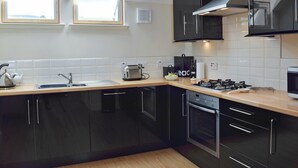 Una cocina moderna con armarios negros, una estufa a gas, un tostador y una tetera.