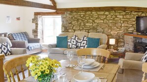 A furnished living room with a stone wall, wooden beams, a fireplace, and a television. - Woodland View-UK11826 (Sarnau, near Brecon)
