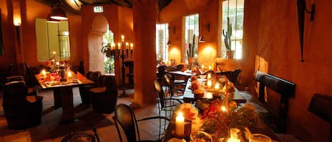 Un restaurante con mesas dispuestas para comer, velas y un ambiente cálido.