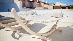 Two white hammocks with cushions on a tiled patio.