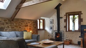 A cozy living room with a stone wall, a fireplace, a sofa, and a coffee table.