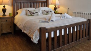 A neatly made bed with pillows, a bedside table with a lamp, and a window with curtains.