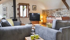 A cozy living room with a fireplace, a television, and a stone wall.