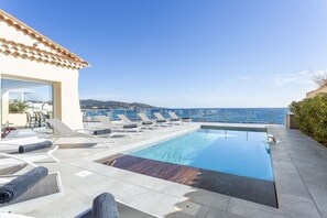 Une piscine sur le toit, dotée de chaises longues et offrant une vue sur la mer.