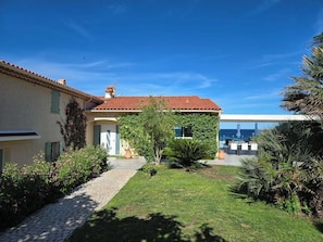 A house with a tiled roof, a paved pathway, and a grassy lawn.