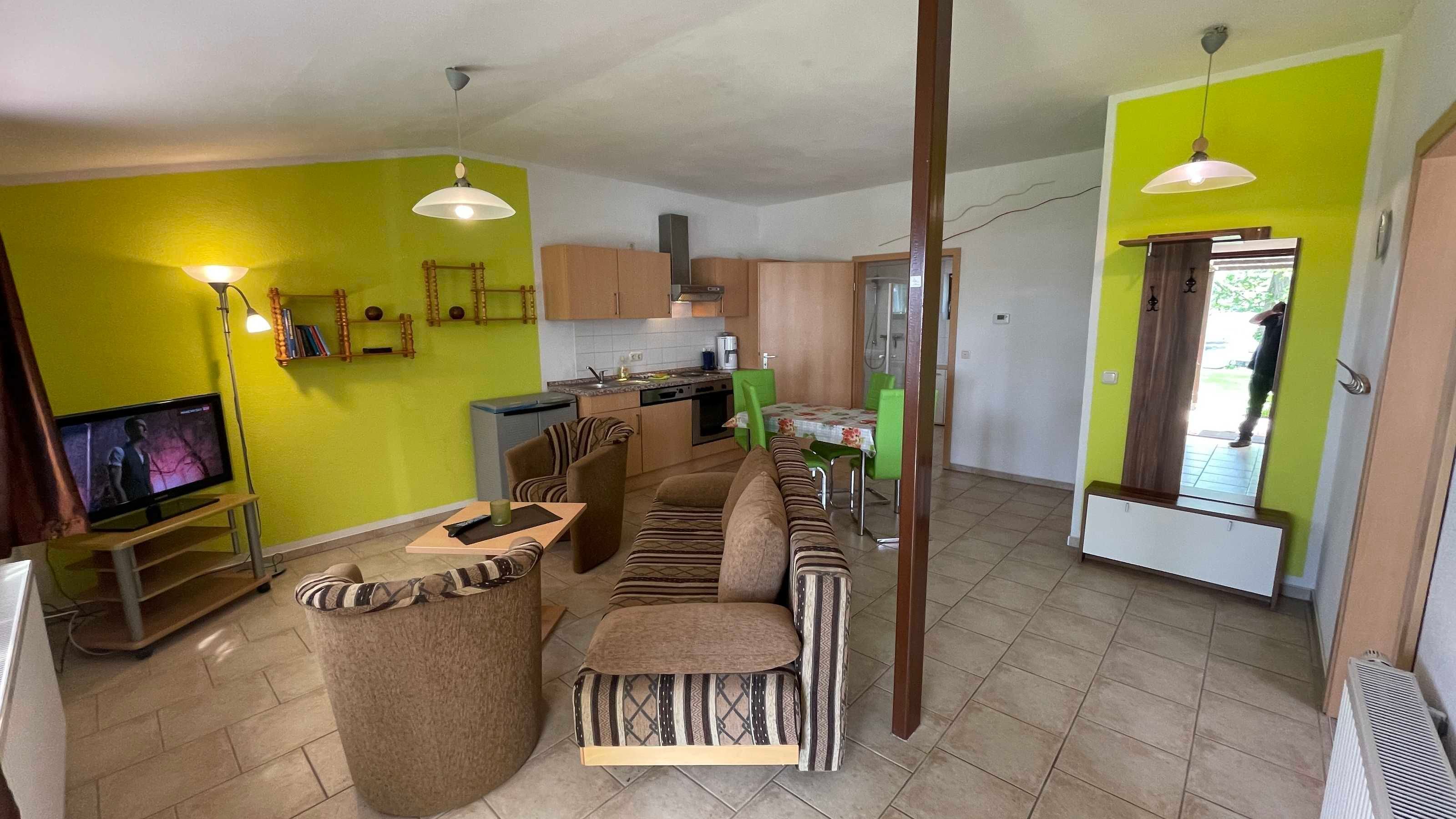 A compact living space with a kitchenette, a sofa set, and a television.