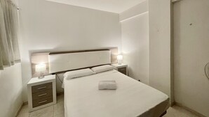 Ein modernes Hotelzimmer mit einem großen Bett, Nachttischen und einem Beistelltischchen mit einer Lampe.
