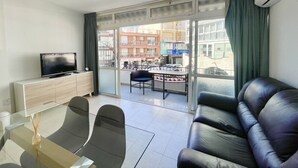 Ein modernes Wohnzimmer mit einer Ledersofa, einem Glastisch und einem Flachbildfernseher.