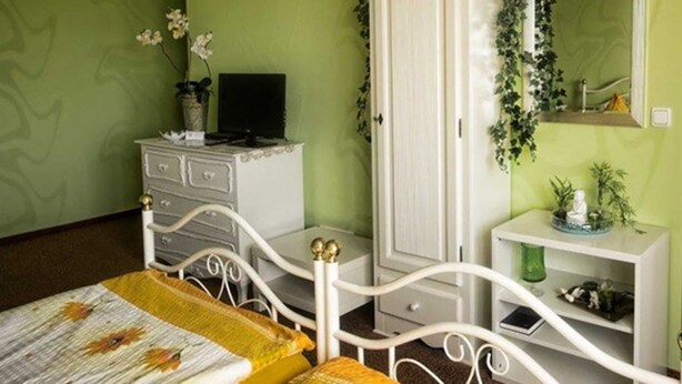 A bedroom with a bed, a dresser, a vanity, and a mirror.