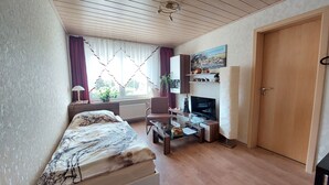 A bedroom with a bed, a desk, a television, and a door.