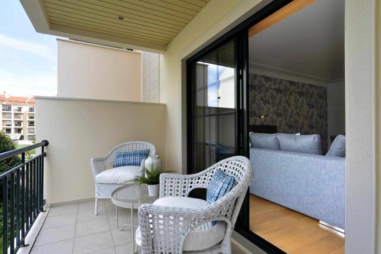 A balcony with wicker furniture, a sofa, and a view of the cityscape.