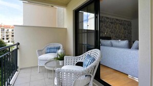 A balcony with wicker furniture, a sofa, and a view of the cityscape.
