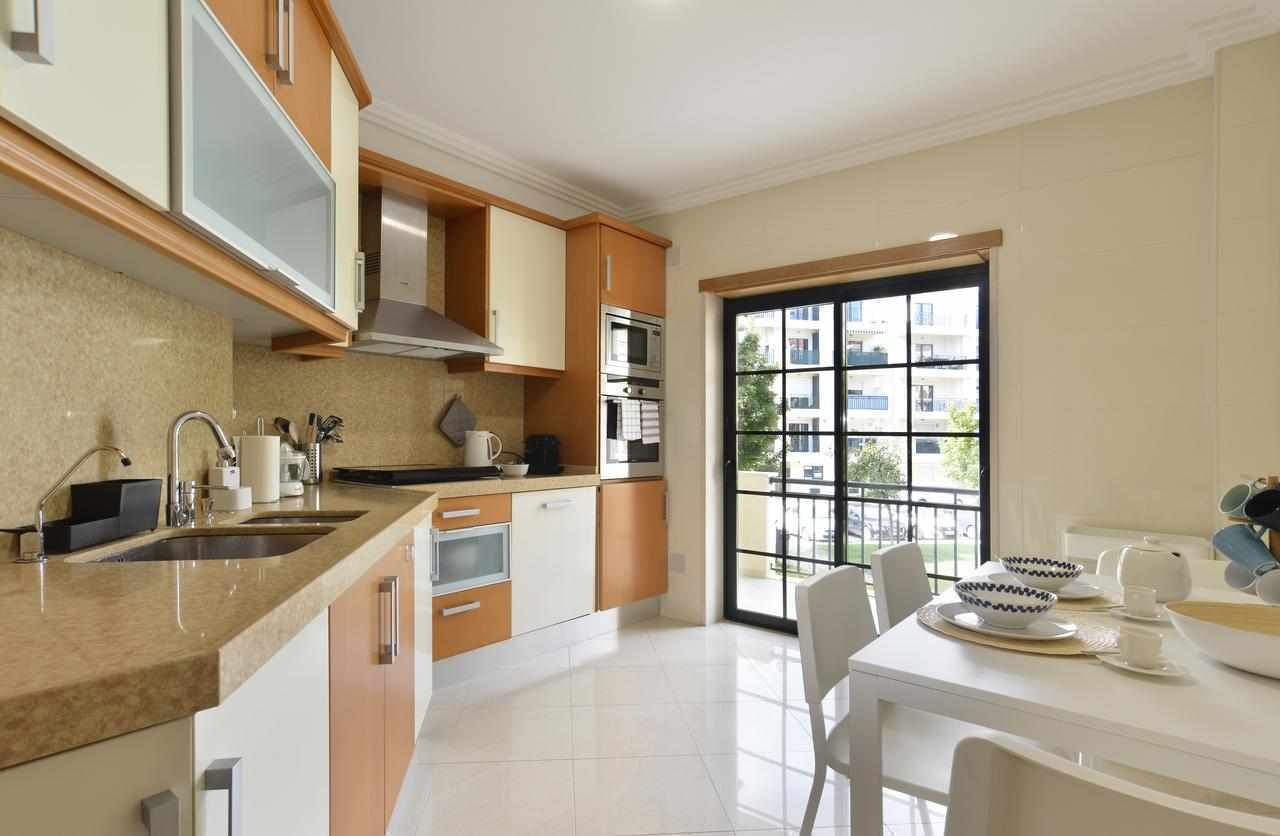 A modern kitchen with a large window, built-in oven, and stainless steel appliances.