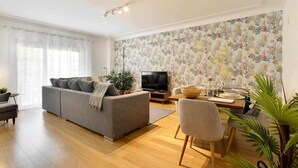 A modern living room with a sofa, TV, dining table, and chairs.