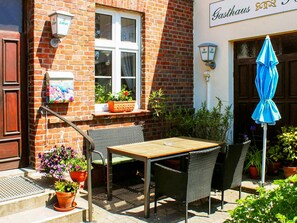 An outdoor seating area with a table and chairs, potted plants, and a blue umbrella. - Double room 5 - Rankwitzer Hof (Rankwitz)