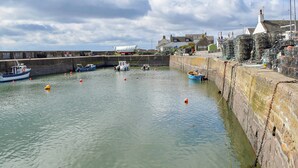 Un puerto con barcos amarrados, un muro de piedra y edificios al fondo.