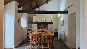 Un comedor con chimenea de piedra, vigas de madera y suelo de piedra.