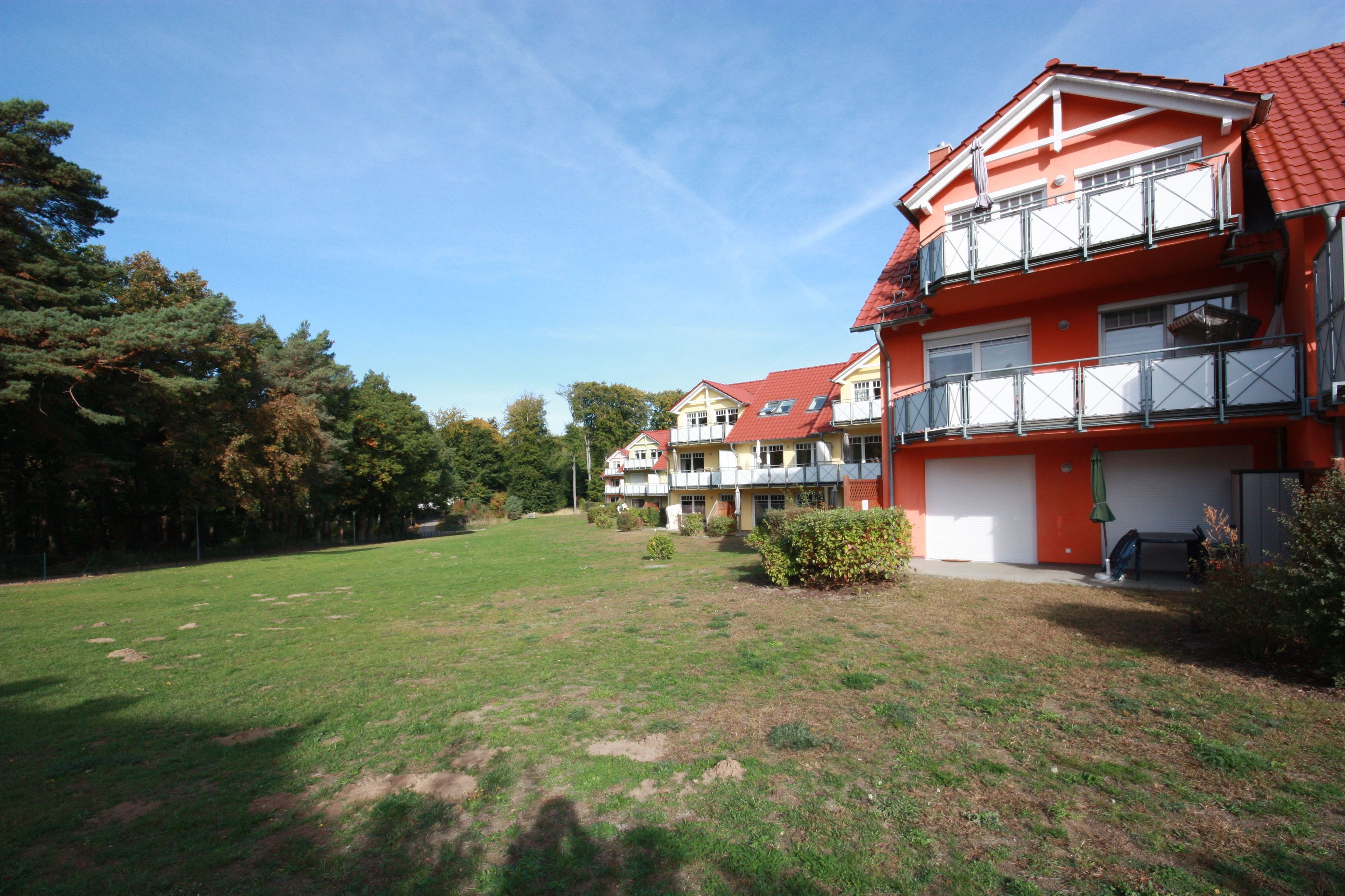 Un immeuble résidentiel à la façade rouge, doté de nombreux balcons et d’une cour verdoyante.