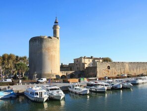 Een historische toren met een minaret, omringd door een versterkte muur en een jachthaven met boten.