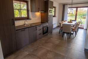 Une cuisine moderne avec des meubles en bois foncé, un évier en acier inoxydable et un coin repas avec des chaises en osier.
