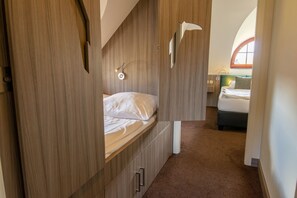 Een slaapkamer met een bed, nachtkastje, wandlamp en raam.