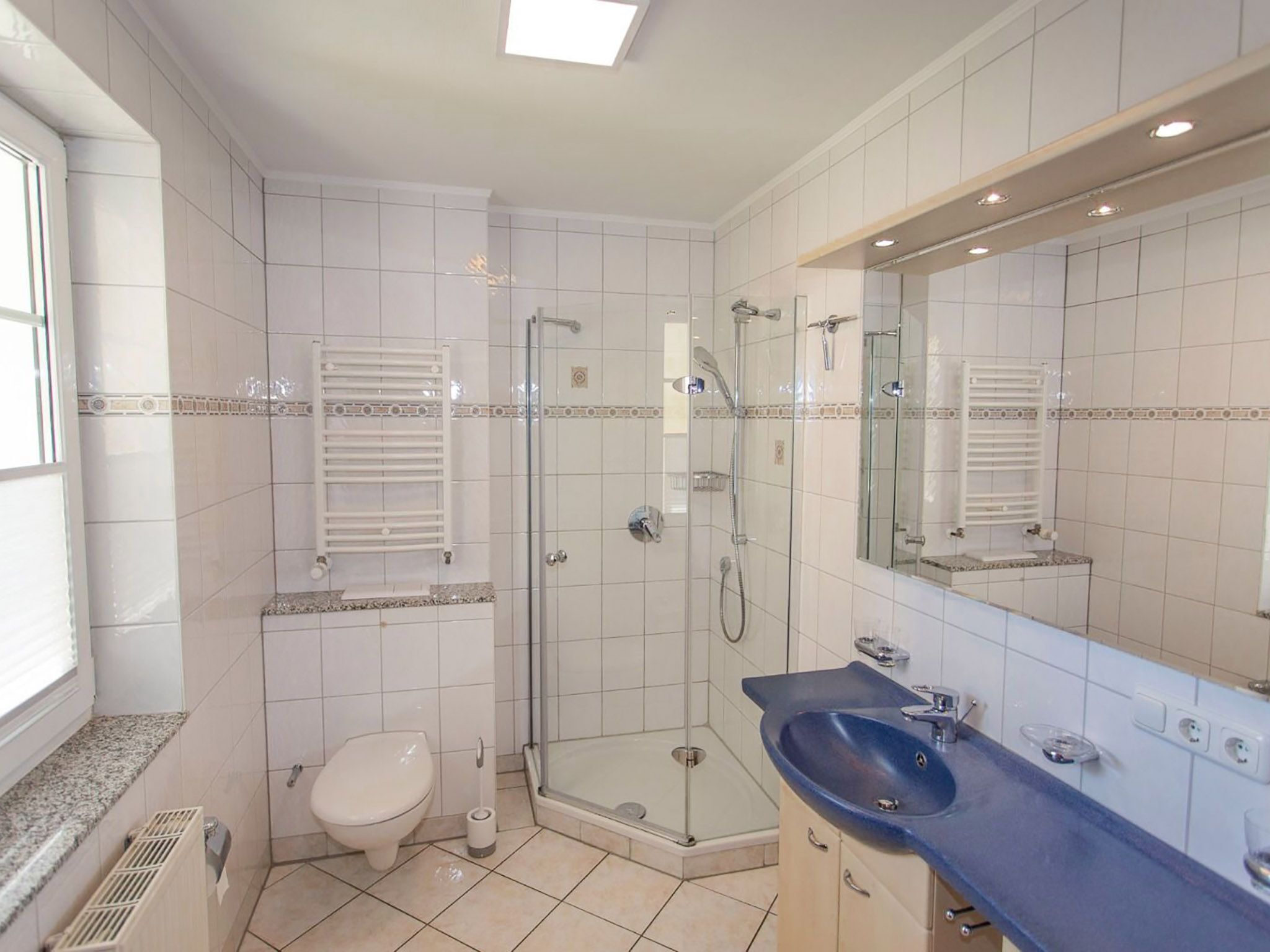 Une salle de bain moderne dotée d’une douche à parois de verre, de toilettes et d’un lavabo avec un grand miroir.