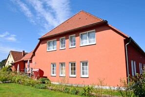 A red two-story house with white windows and a red roof.