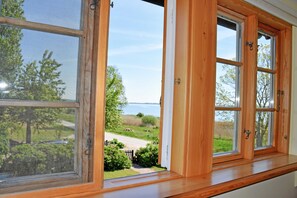 A window with a view of a grassy area and a body of water.