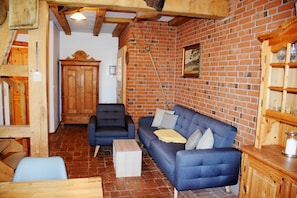 A rustic room with a brick wall, wooden furniture, a blue sofa, and a wooden cabinet.