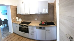 A compact kitchen with a wooden countertop, two sinks, a coffee maker, and a dishwasher. - Apartment 2 (2 rooms) - Meutzner Trassenheide, Villa Seute Deern (Trassenheide)
