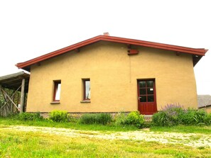 A single-story building with a red roof, two windows, and a red door. - Single room Benedikt - House Lehmkloster am Wangeliner Garten with 5 single rooms (Buchberg)