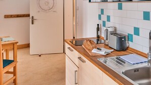 Una cocina con mostrador de madera, hogaza de pan, tostadora y un lavabo.
