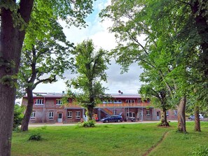 Un edificio de dos pisos con fachada de ladrillo, rodeado de árboles y césped.