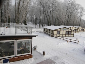Un bâtiment enneigé doté d’un balcon, d’une clôture en bois et d’une enseigne sur laquelle on peut lire « Ferienhäuser ».