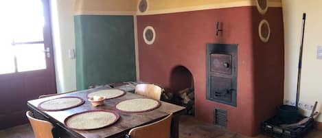 Un comedor con una mesa de madera, individuales tejidos y sillas acolchadas.
