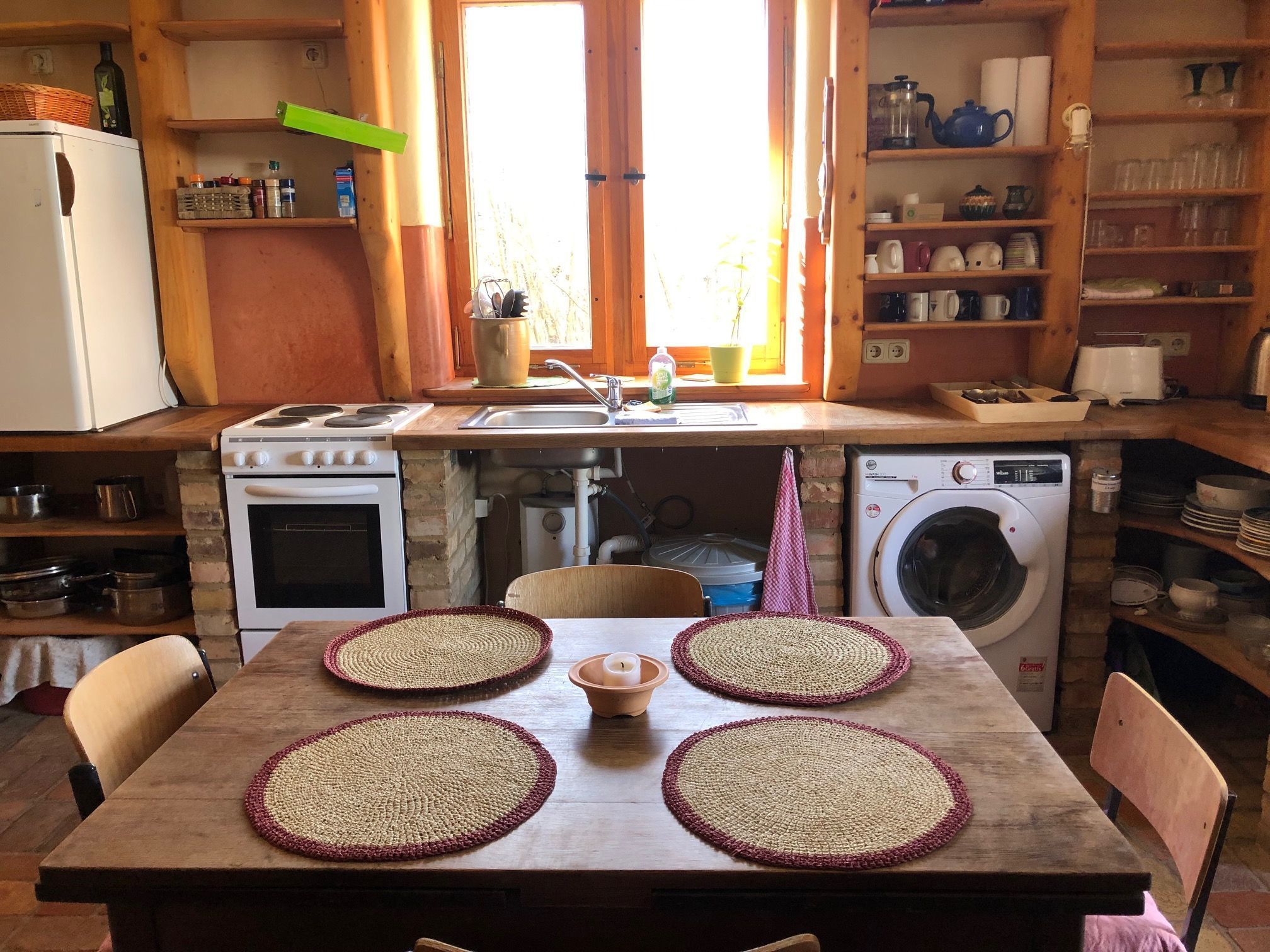 A compact kitchen with a stove, oven, sink, and washing machine.