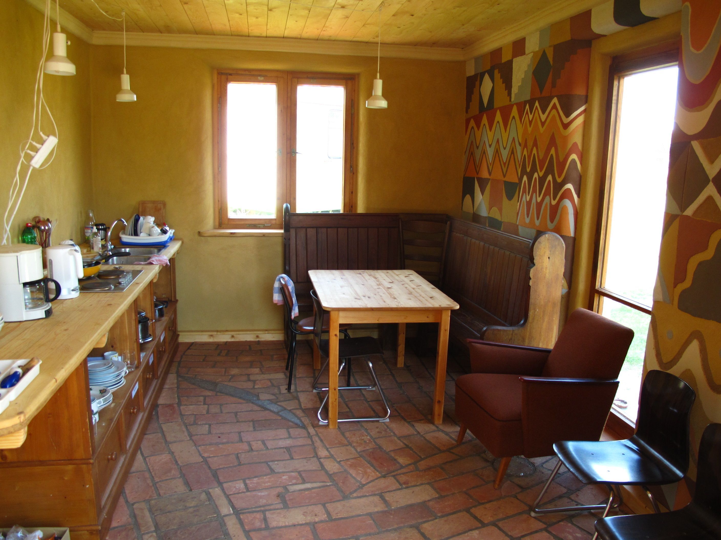 A kitchen with a wooden table, chairs, a bench, and a window with a view.