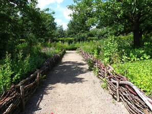A gravel path flanked by wooden fences and lush greenery. - Single room Don Bosco - House Lehmkloster am Wangeliner Garten with 5 single rooms (Buchberg)
