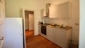 Una cocina compacta con armarios blancos, un lavamanos de acero inoxidable y un horno empotrado.