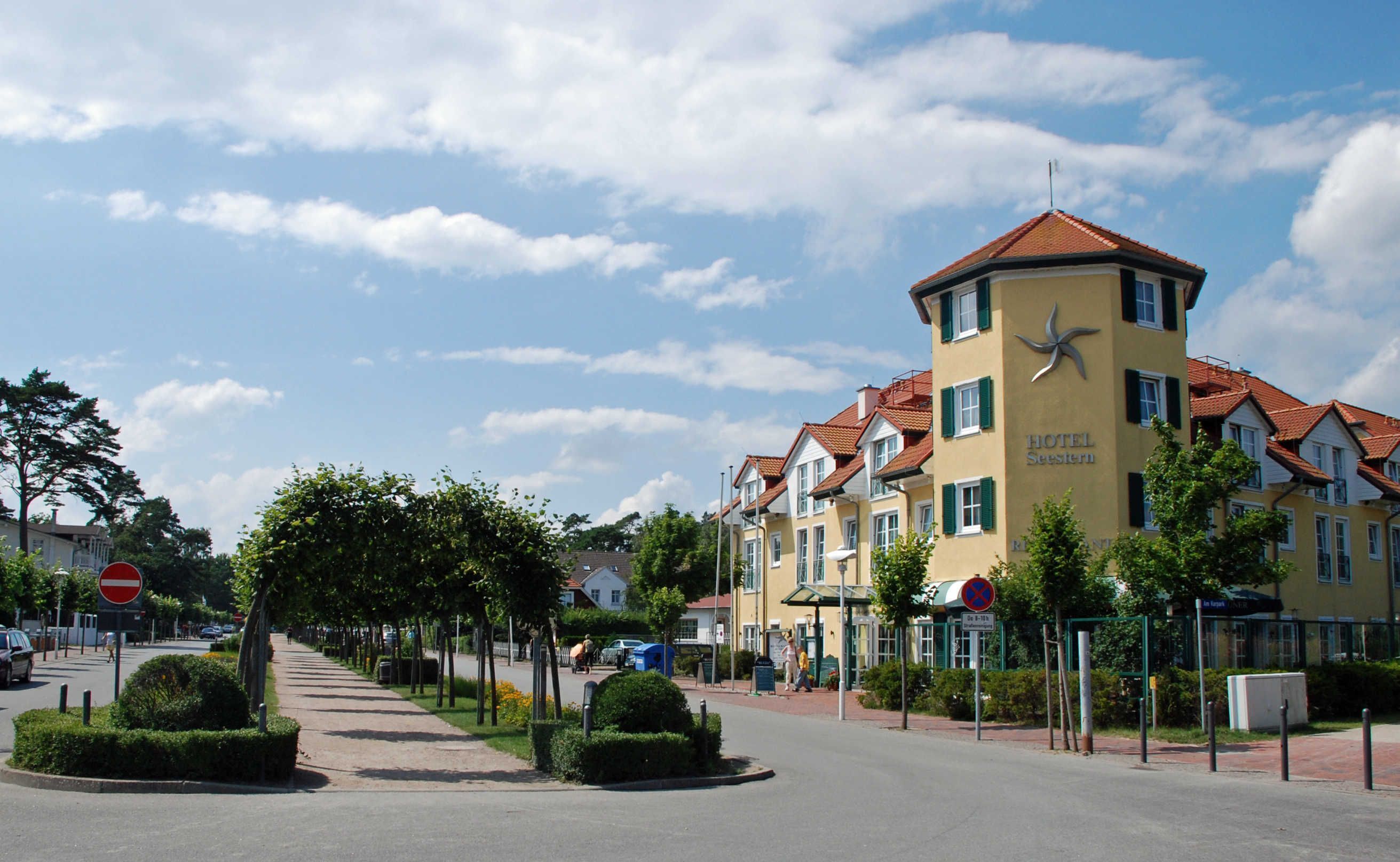 A hotel with a yellow facade, red-tiled roof, and a star logo.