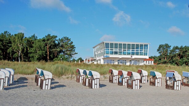 A beachside building with a modern design, rows of beach chairs, and a clear view of the ocean. - 05 Single room - Villa in the Ostseebad Baabe (Baabe)