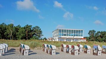 Ein Gebäude am Strand mit modernem Design, Reihen von Liegestühlen und freiem Blick auf den Ozean.