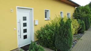 Un edificio amarillo con una puerta blanca y tres ventanas.
