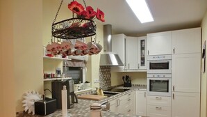 Una cocina moderna con armarios blancos, una isla central, un arreglo floral colgante y un horno empotrado.